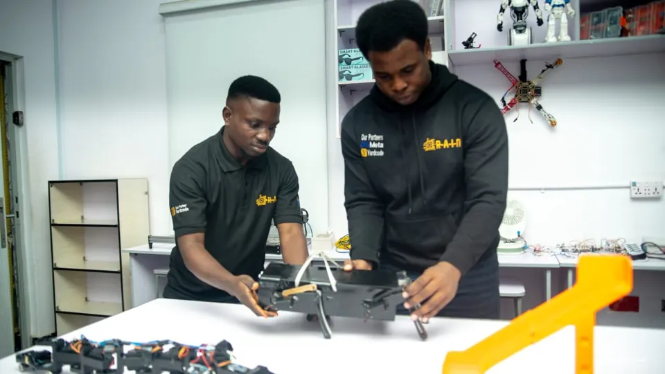 Two RAIN trainees assembling a robot in the lab
